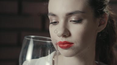 肖像漂亮的女人嗅探葡萄酒杯喝红色的酒关闭